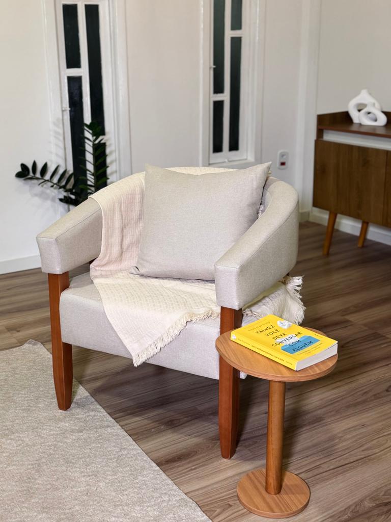 Poltrona com manta e mesa lateral com livro no consultório